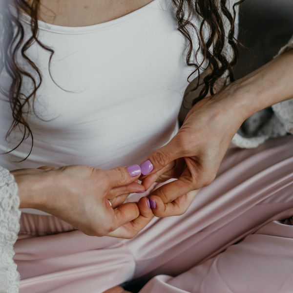 Close-up of two people's hands gently supporting each other in a yoga pose.